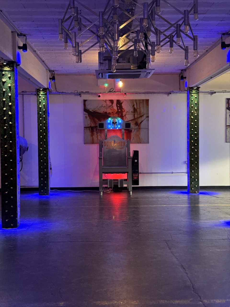 Screamer electric chair game set up in a venue with coloured lighting