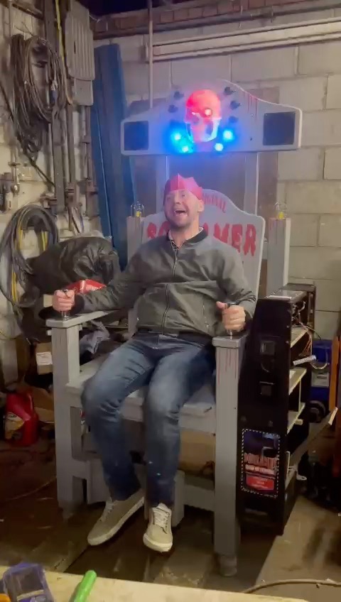 Player in a paper crown reacting while gripping the shock chair handles